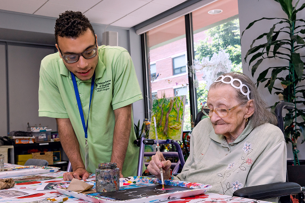 Team member supporting a resident during a painting and arts activity in memory care