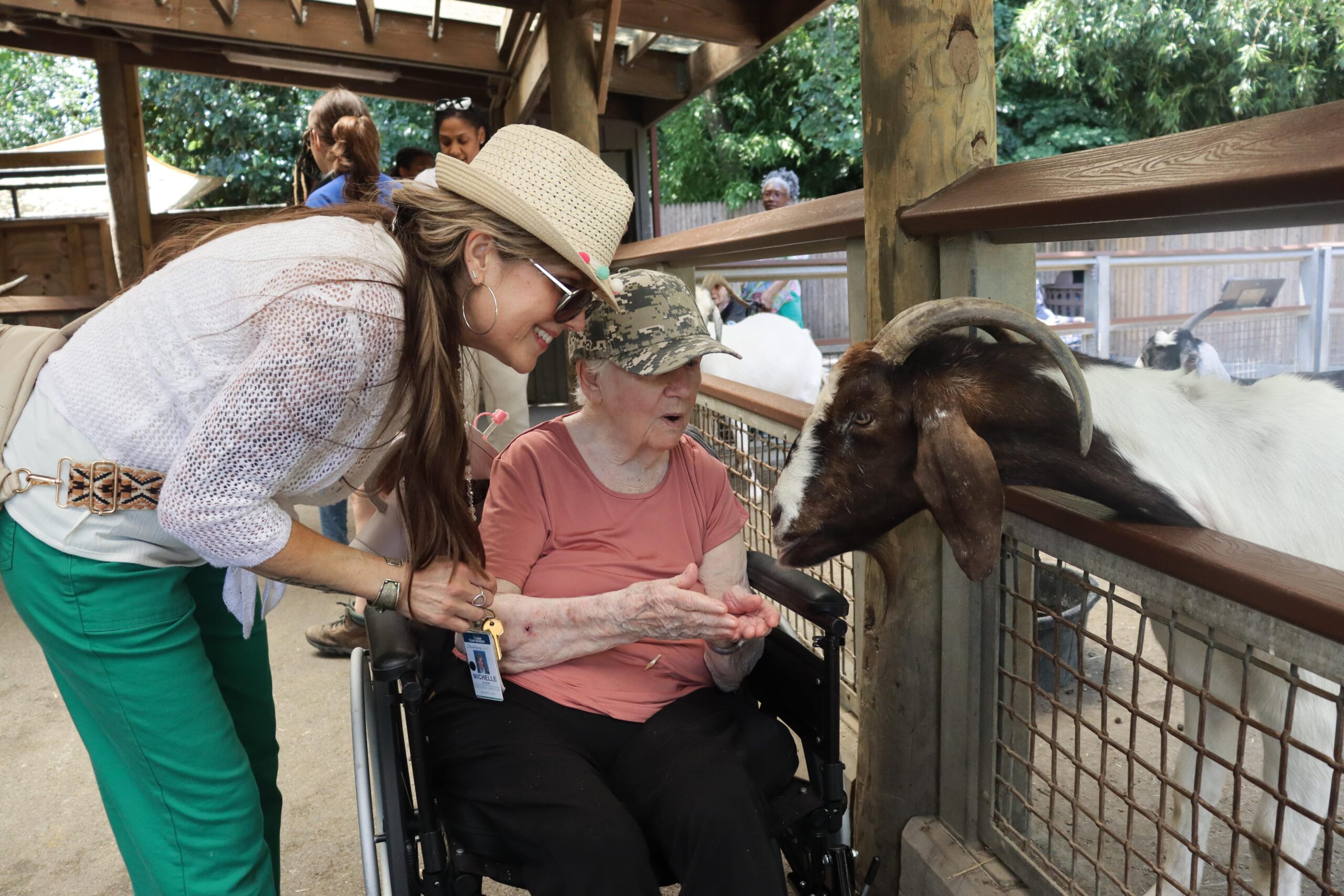 Older adult interacting with a goat during an outdoor senior living activity