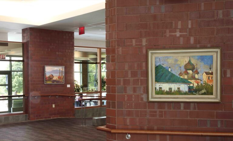 Landscape, Chagall, and Soviet-era paintings on red brick walls in a bright, modern building with large windows.